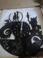 Front view of cut-out vinyl record wall clock showing design and hands