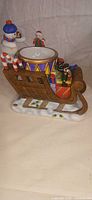 Side view of Partylite sleigh music box with snowman, bowl, gifts