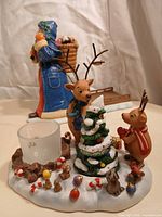 Front view of reindeer tealight holder vignette with Santa figurine blurred behind