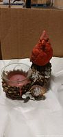 Front view of resin cardinal candle holder with glass votive and red candle