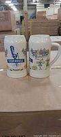 Front view of both steins showing Steam Whistle logo and Oktoberfest graphics