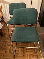 Two green upholstered chairs on metal sled bases