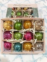 Open box showing 12 assorted color ornaments in compartments