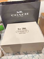 Coach black shopping bag and off-white gift box front view