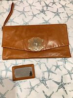 Front view of clutch with wrist strap and matching mirror/card holder