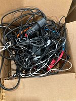 Box filled with tangled electric cords and accessories