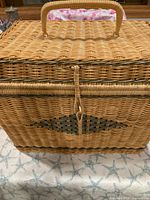 Front view of rattan picnic basket showing lid, handle and decorative weave