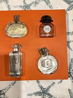 Four Hermes miniature perfume bottles on orange background