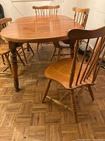 Full view of oak dining table with leaf inserted showing turned legs and light oak finish