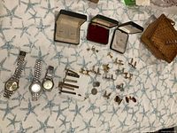 All items laid out showing watches, cufflinks, tie bars, coins, cases
