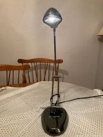 Full view of chrome LED desk lamp illuminated on table