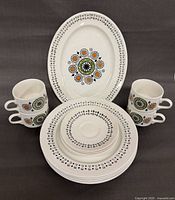 Full set staged: platter at back, two mugs, stacked plates