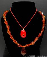 Both necklaces displayed on black bust, showing overall look and pendant positions