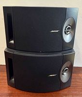 Front view of stacked speakers showing grilles, tweeter lenses and logos