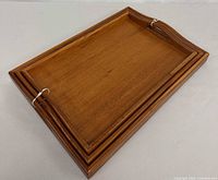 Three stacked teak trays showing nesting design and handles