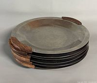 Stack of six stainless plates showing wood handles