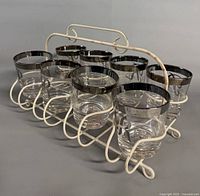 Oblique view of eight glasses seated in white wire caddy