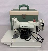 Front/left view of Singer Featherweight 221K with cords, case behind