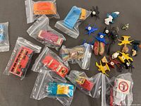Group view of bagged diecast vehicles and loose plastic figurines