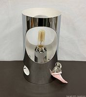 Front view of chrome cylindrical touch lamp with bulb and cord visible