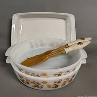 Two Termo Rey casseroles stacked, Corning Ware lid behind, two spatulas inside