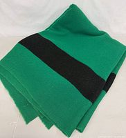 Folded green blanket with black stripe showing woven edges