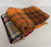 Two folded textiles showing different plaid patterns