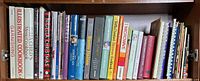 Full shelf of assorted cookbooks showing spine titles and formats