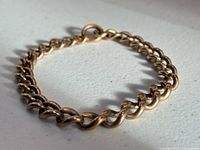 Bracelet coiled to show thickness of curb links and clasp ring