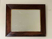 Full view of mirror showing wood frame, gold inner trim, and glass surface