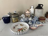 Group shot showing all ceramic, stoneware, glass, metal and wicker items in the lot