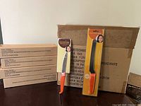 Carded 5" utility knife, carded 7" bread knife, shipping cartons in background