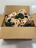 Open cardboard box filled with individually tagged Christmas tree and snowman shaped loofah kitchen scrubbers