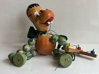 Full view of Pelham Puppets baby dragon marionette seated with control bar and strings