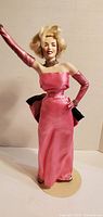Front view of Marilyn Monroe Franklin Heirloom doll in pink gown on stand