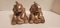 Front view of both nickel-plated elephant bookends seated with trunks up