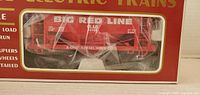 Front view of boxed red Big Red Line OL&B ore car through window