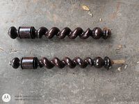 Two dark mahogany barley-twist spindles on concrete floor