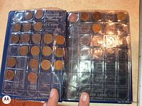 Open album showing pockets with coins and empty slots