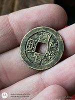 Obverse of bronze Chinese cash coin held in hand