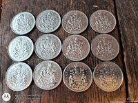 Twelve Canadian 50-cent coins, reverse side up showing coat of arms