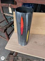 Full view of cylindrical vase upright showing red and yellow oval accents
