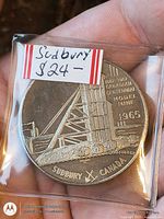 Front of 1965 Sudbury nickel coin in plastic flip showing mine headframe and inscriptions