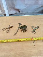 All four brass pieces laid out with tape for scale