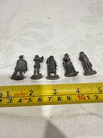 Five pewter knight miniatures lined up with measuring tape showing size