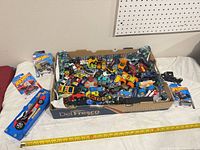 Box full of loose cars with sealed items placed around it