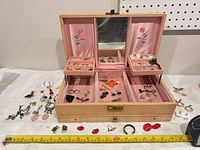Open jewelry box with assorted jewellery displayed, measuring tape for scale