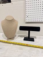 Front view of necklace bust and bracelet T-bar with tape for scale