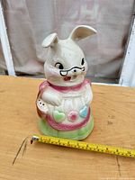 Front view of ceramic bunny cookie jar with tape measure showing height