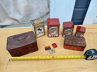 All eight tins arranged with tape measure for scale